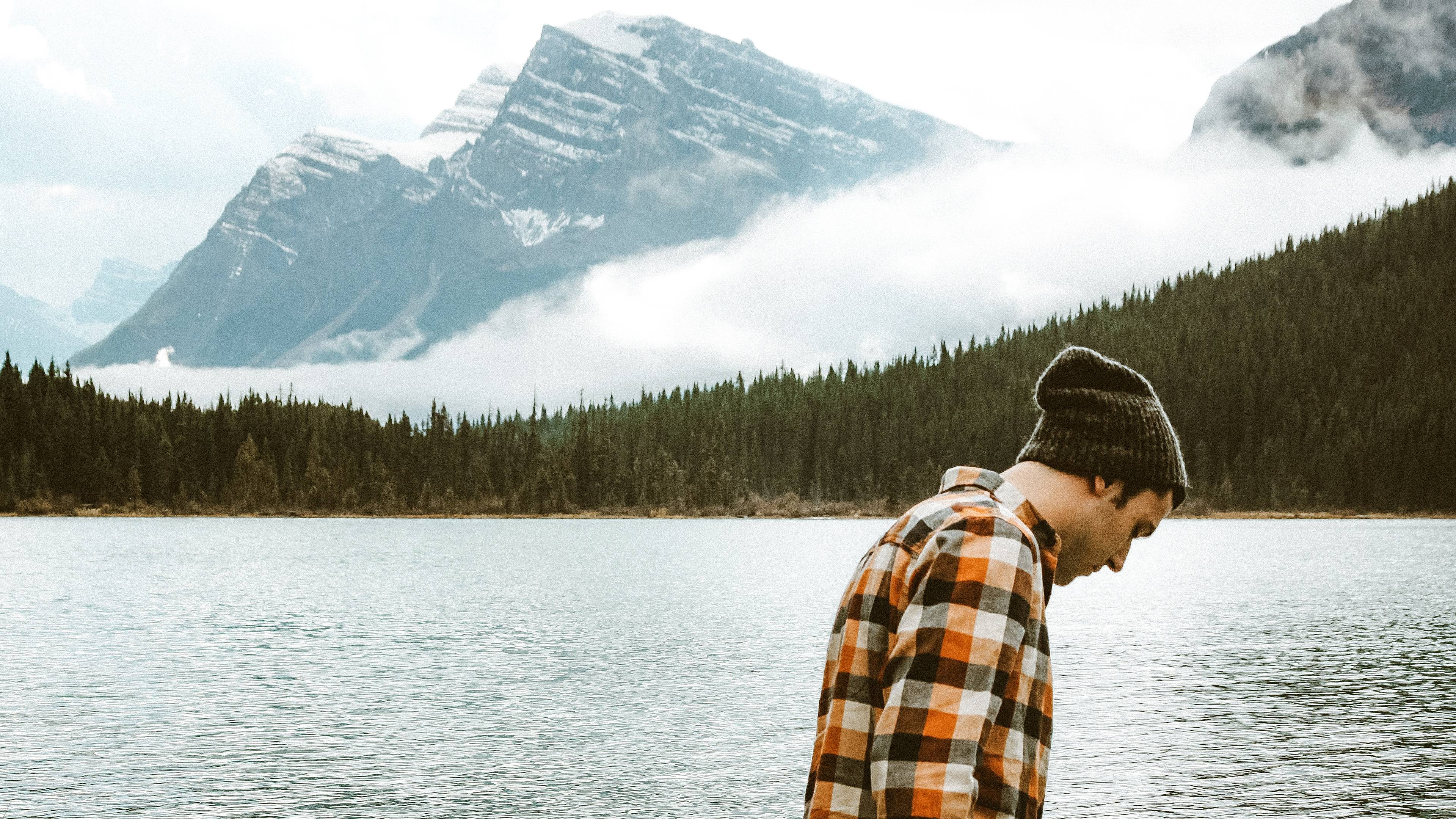 Un homme de profil devant un paysage de lac et de montagnes